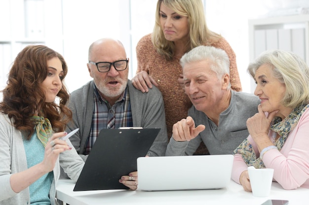 Foto dois casais seniores conversando com um consultor enquanto estão sentados à mesa