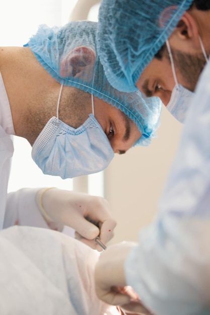 Dois cirurgiões em vestes azuis operam na sala de cirurgia