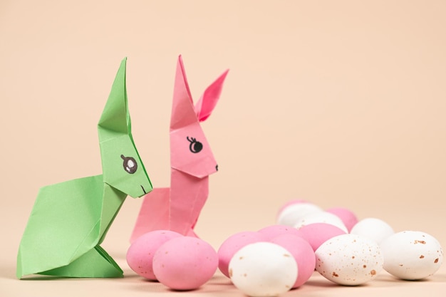 Dois coelhinhos de origami de papel e um ovo de Páscoa em um fundo bege