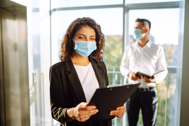 Foto dois colegas de trabalho com máscaras protetoras discutindo o projeto, compartilhando ideias.