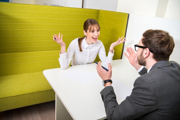 Dois colegas de trabalho discutindo e sentando à mesa