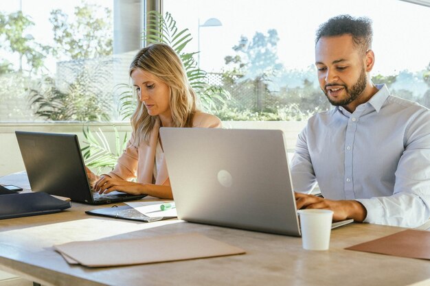 Foto dois colegas de trabalho usando seus laptops enquanto trabalham no escritório conceito comercial