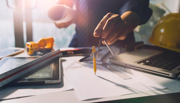 Dois colegas discutindo trabalho de dados e tablet laptop com projeto arquitetônico no canteiro de obras na mesa no escritório