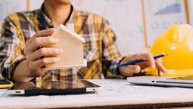 Dois colegas discutindo trabalho de dados e tablet laptop com projeto arquitetônico no canteiro de obras na mesa no escritório