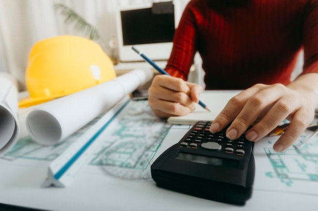 Dois colegas discutindo trabalho de dados e tablet laptop com projeto arquitetônico no canteiro de obras na mesa no escritório