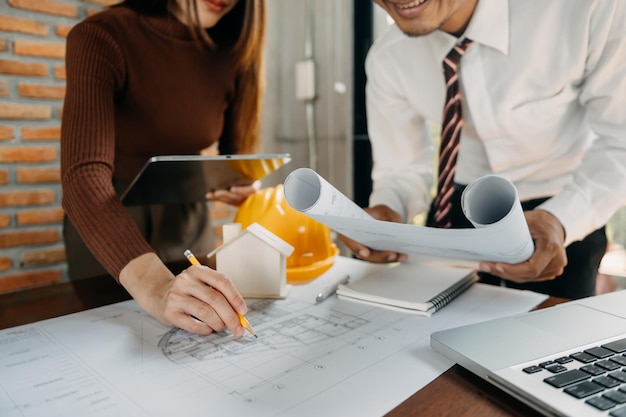 Dois colegas discutindo trabalho de dados e tablet laptop com projeto arquitetônico no canteiro de obras na mesa no officexAxA