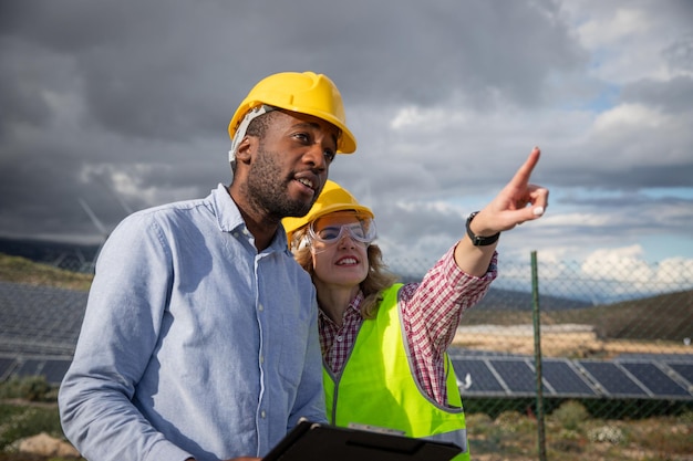 Foto dois colegas em uma usina de energia solar trabalham na indústria internacional de energia renovável