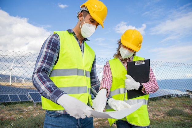 Dois colegas trabalham em uma usina de energia solar e analisam um projeto de cooperação e parceria