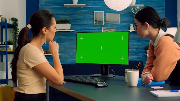 Dois colegas trabalhando juntos no computador com simulação de display de chroma key de tela verde para publicidade em mídia social