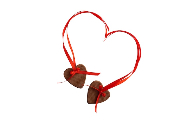 Dois cookies de coração com fitas vermelhas, isoladas no fundo branco.