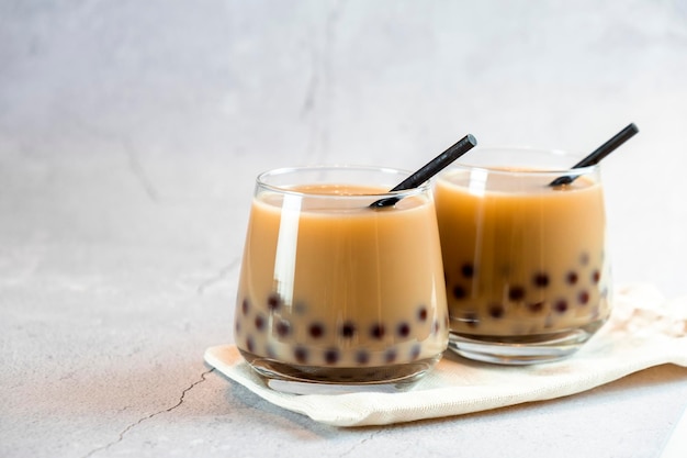 Dois copos com chá de bolha de leite com deliciosas pérolas de tapioca na placa de madeira Famoso chá de geléia de leite de Taiwan Bebidas saborosas com espaço de cópia