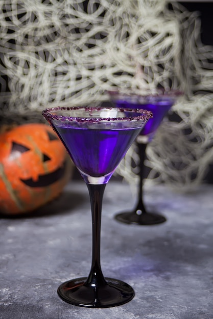 Dois copos com cocktail roxo, abóbora para festa de Halloween