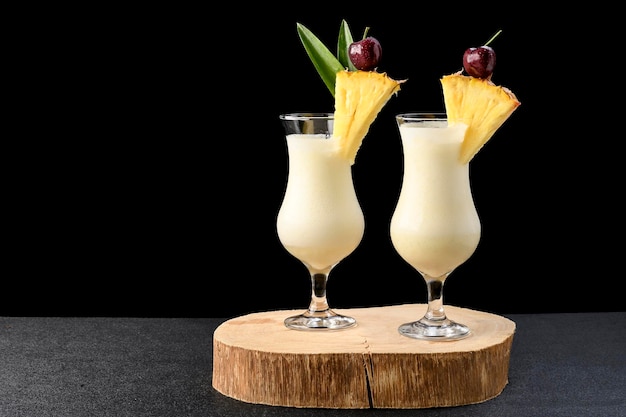 Dois copos com coquetel pina colada isolado no fundo preto