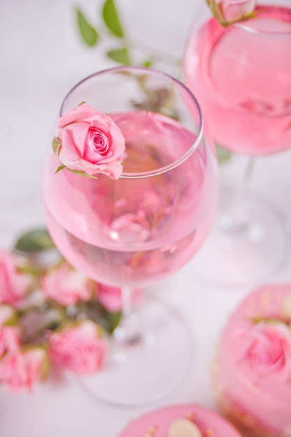 Foto dois copos com vinho de uva rosa com flores rosas. conceito de jantar romântico.