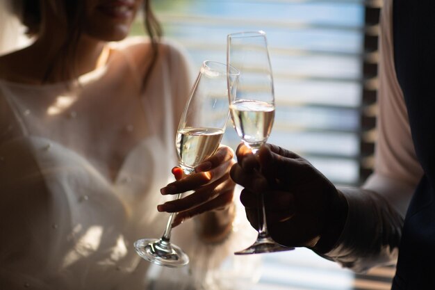 Dois copos com vinho espumante nas mãos de recém-casados