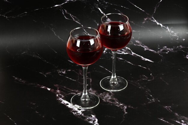 Dois copos com vinho tinto em um fundo escuro