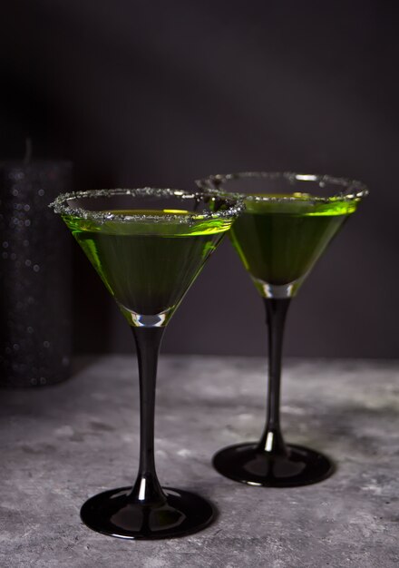 Dois copos com zumbi verde cocktail para festa de Halloween no fundo cinza