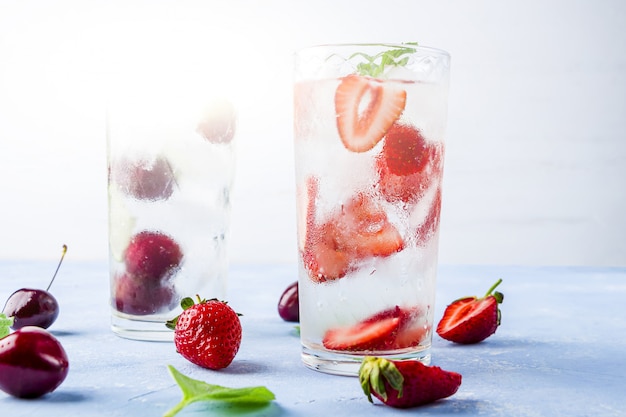 Dois copos de bebida refrescante de desintoxicação com morango, cereja e hortelã