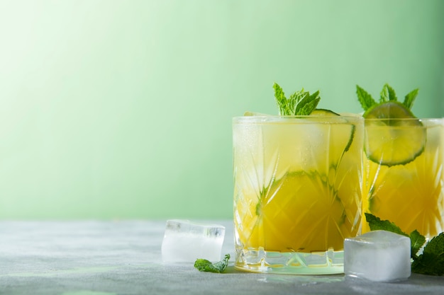 Dois copos de bebidas refrescantes com cubos de gelo, suco e frutas de limão, coquetel de festa. Copie o espaço