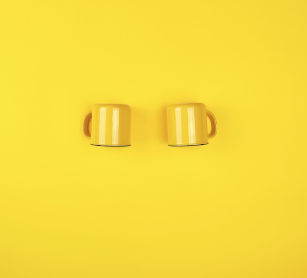 Dois copos de cerâmica amarelos com uma alça em amarelo