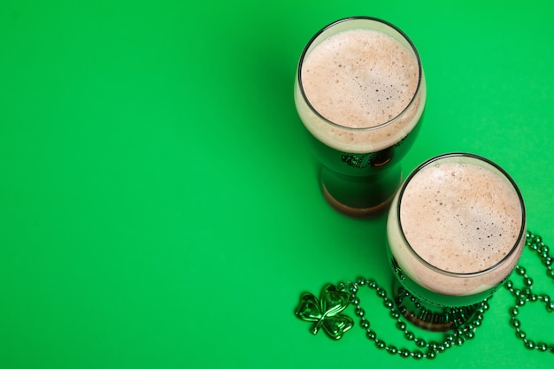 Dois copos de cerveja preta forte e decoração tradicional em forma de trevo, composição festiva do Dia de São Patrício