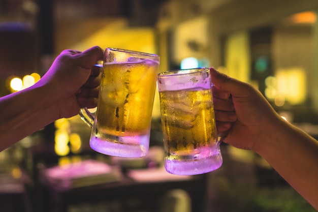 Foto dois copos de cerveja vibra juntos entre amigo no bar de baixa luz e restaurante