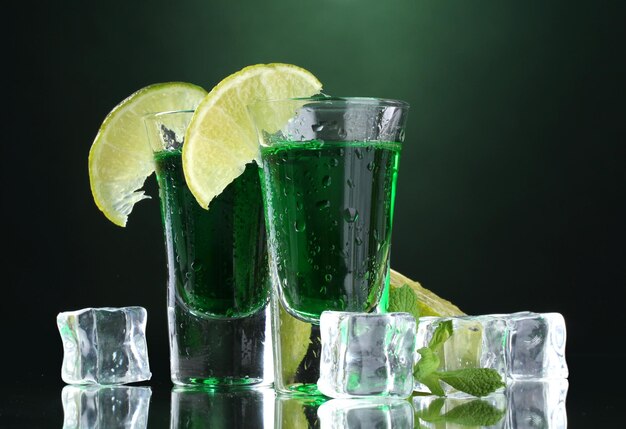 Dois copos de limão absinto e gelo sobre fundo verde