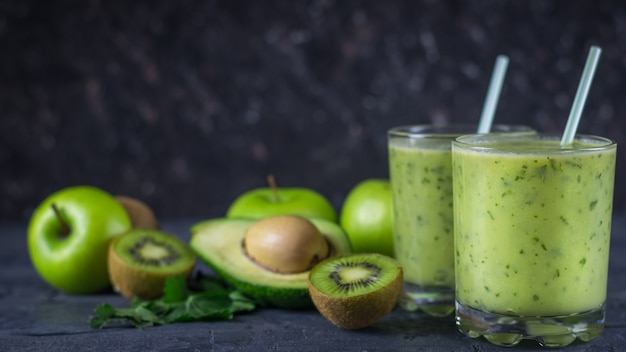 Dois copos de vidro cheio de suco de abacate na mesa de madeira com frutas. Faça dieta comida vegetariana.