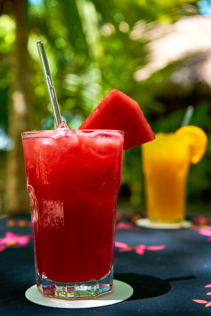 Dois copos de vidro com bebidas refrescantes de suco de laranja e melancia.