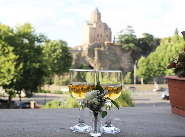 Dois copos de vinho branco e flores lá fora em um dia ensolarado