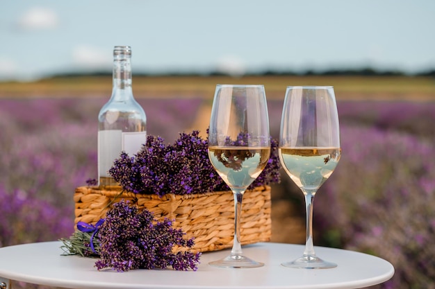 Dois copos de vinho branco e garrafa em um campo de lavanda em flores Provance Violet no fundo