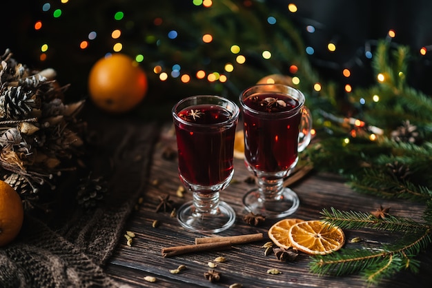 Dois copos de vinho quente quente em uma mesa de madeira decorada de Natal