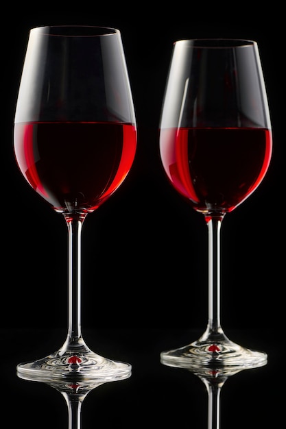 Dois copos de vinho tinto em uma mesa lustrosa. fundo preto.