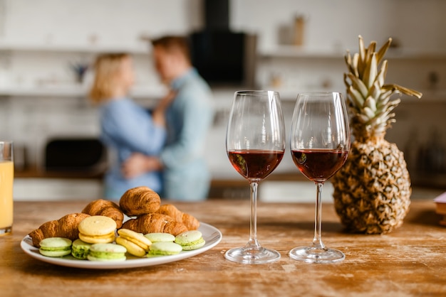 Dois copos de vinho tinto na mesa, casal apaixonado se abraçando