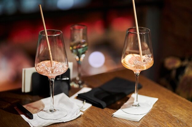 Dois copos meio vazios com gelo e uma rodela de laranja sobre a mesa de um bar