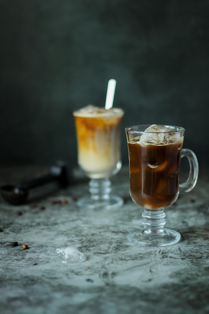 Dois copos transparentes com um café gelado preto caseiro e café frio e creme