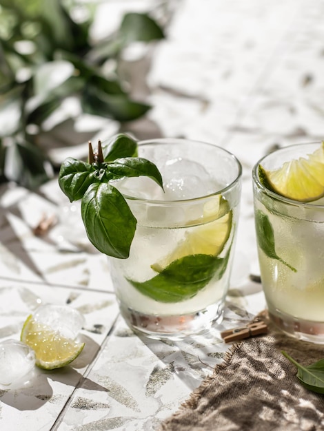 Dois coquetéis de margarita com limão e manjericão em copos fecham em azulejo impresso