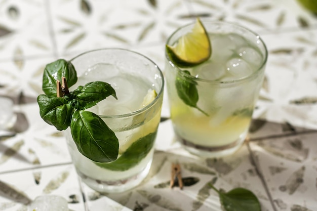 Dois coquetéis de margarita com limão e manjericão em copos fecham em azulejo impresso