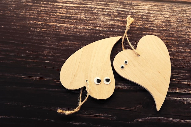 Dois corações de madeira engraçados com olhos em um fundo de madeira. Cartão de dia dos namorados.