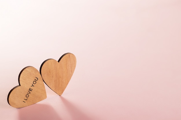 Dois corações de madeira no fundo rosa