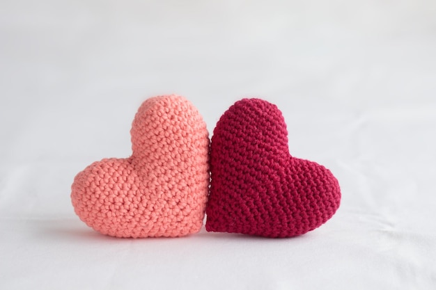 Dois corações rosa amigurumi de crochê em um fundo branco Bandeira do dia dos namorados