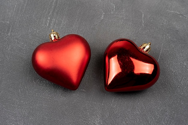 Dois corações vermelhos em um fundo cinza de concreto. Plano de fundo de decoração de Natal para cartão-presente.