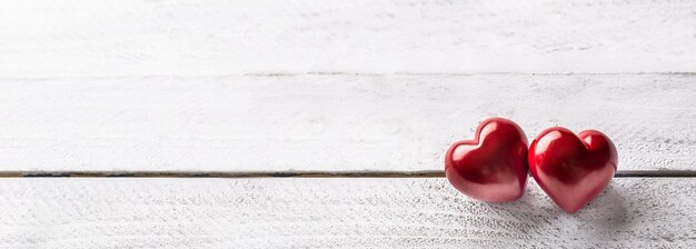 Dois corações vermelhos na mesa de madeira. banner panorâmico romântico para manobristas ou dia do casamento.