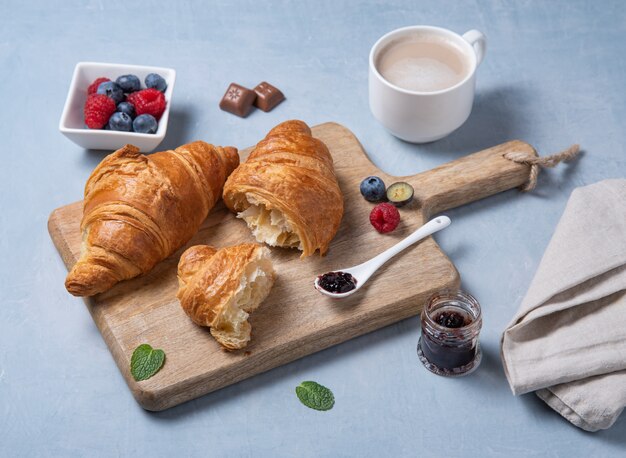 Dois croissants com uma xícara de café e frutas