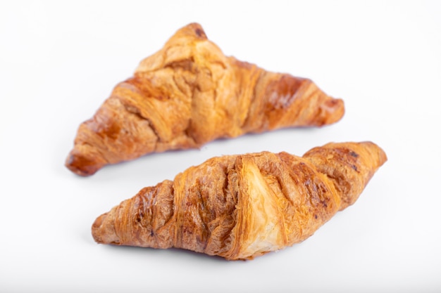 Dois croissants frescos e saborosos colocados sobre um fundo branco.