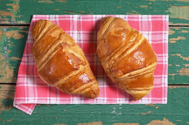 Dois croissants recém-assados na velha vista superior de fundo verde de madeira