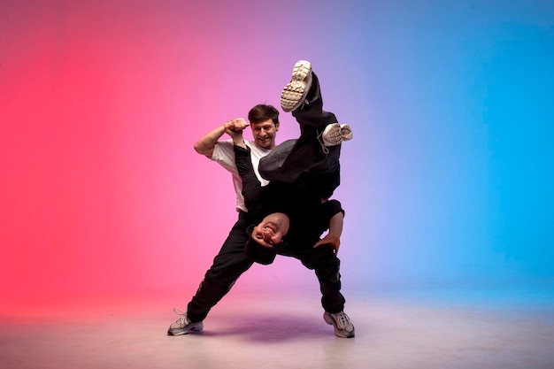 Dois dançarinos dançam break em fundo azul vermelho e enganam acrobatas masculinos