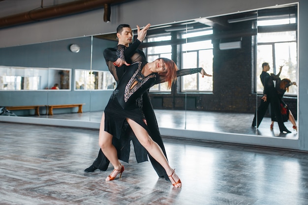 Dois dançarinos de elegância em trajes no treinamento de dança ballrom em classe.