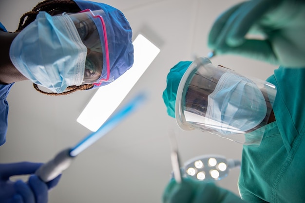 Dois dentistas africanos com ferramentas dentárias à disposição durante uma visita odontológica ponto de vista do paciente