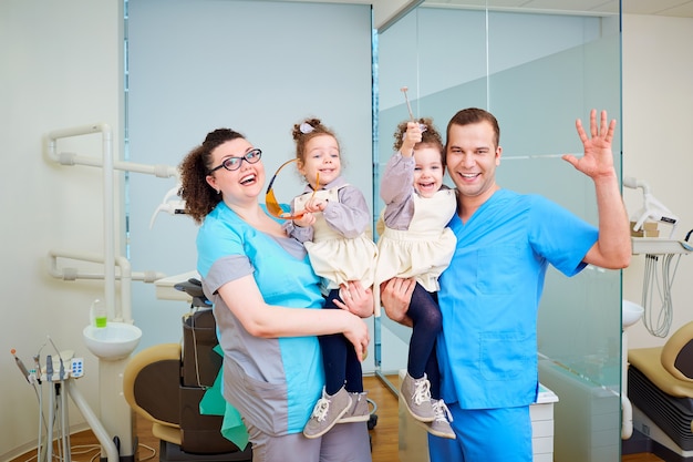 Dois dentistas com crianças nos braços sorrindo e rindo d